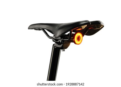 Close-up of bicycle saddle and illuminated tail light on white background