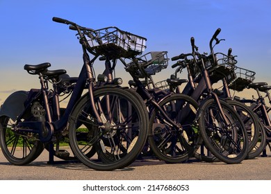 Close-up Bicycles Stand In The Parking Lot Against The Backdrop Of A Beautiful Sky. No People . Bike With A Basket For Things