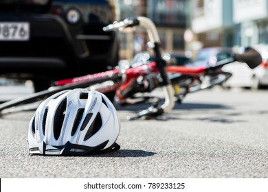 Close-up of a bicycling helmet fallen on the asphalt  next to a bicycle after car accident on the street in the city