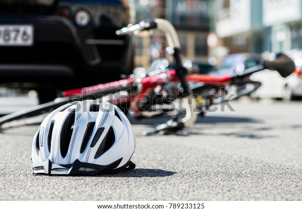 Close-up of\
a bicycling helmet fallen on the asphalt  next to a bicycle after\
car accident on the street in the\
city