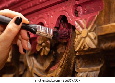 Closeup Of Big Brush In Woman Hand Coloring Rusty Carved Ornaments Of Wooden Sideboard Buffet In Pink Color. New Life Of Old Things. Restoration Of Antique Old Furniture Pieces.