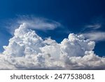 Closeup of Billowy cumulus clouds. Wispy clouds, deep blue sky in background. 
