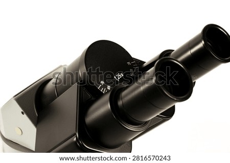 Close-up of binocular microscope eyepieces with adjustable interpupillary distance and magnification settings. Professional optical laboratory equipment isolated on white.