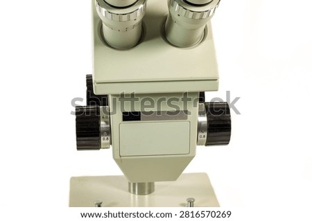 Close-up of a binocular stereo microscope head with precision zoom adjustment controls. Professional optical equipment isolated on white for laboratory, industrial inspection and research.