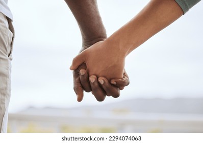 Closeup of biracial couple interlocking fingers and holding hands while bonding outdoors. Caring mixed race woman united with african american man. Together in support and a loving relationship - Powered by Shutterstock