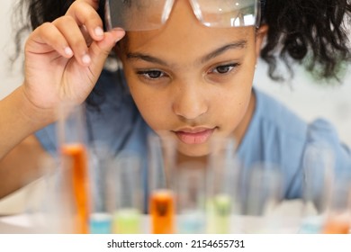 Close-up of biracial elementary schoolgirl looking at chemicals in test tubes during chemistry class. unaltered, education, learning, scientific experiment, stem, protection and school concept. - Powered by Shutterstock