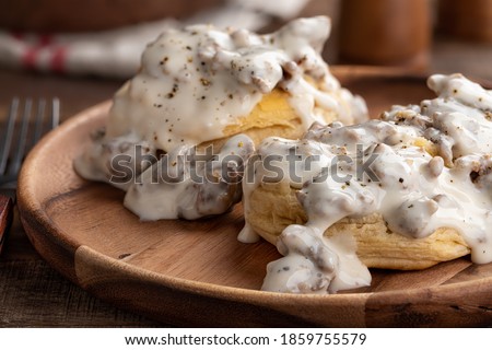 Closeup of biscuits and creamy sausage gravy on a wooden plate 