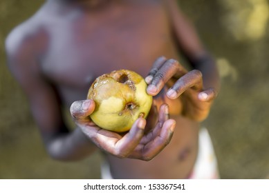 Closeup of black african child holding rotten apple.