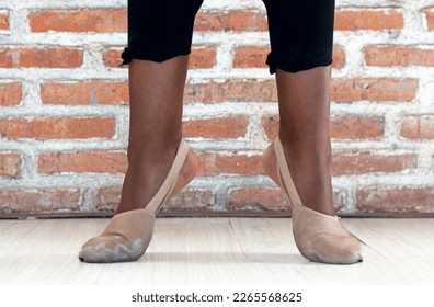 Close-up of a Black American female ballet dancer's feet in worn pointe shoes, as she holds a position at a dance studio in Bali, Indonesia - Powered by Shutterstock