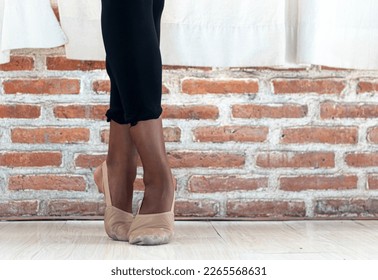 Close-up of a Black American female ballet dancer's feet in worn pointe shoes, as she holds a position at a dance studio in Bali, Indonesia - Powered by Shutterstock