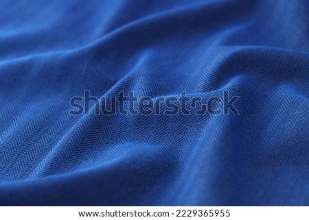 Close-up of black and blue herringbone fabric texture background. Pattern of wavy cloth backdrop for design art work
