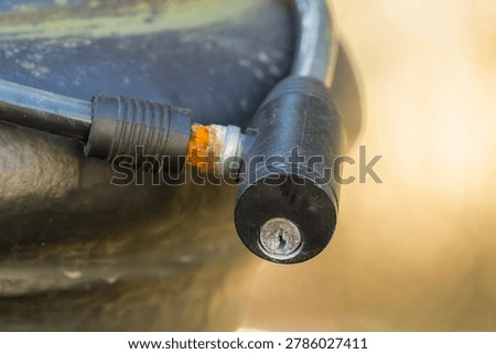Close-up of a black cable lock with visible rust at the connection point.