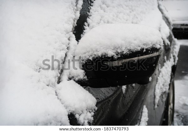 Close-up of a black car rear view mirror covered in
white snow