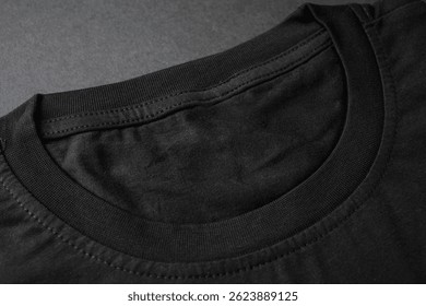 Close-up of black cotton t-shirt collar on dark background