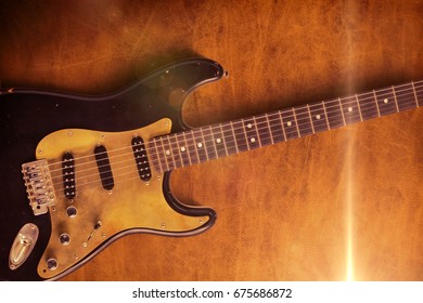 A closeup of a black custom electric guitar on a leather background. - Shutterstock ID 675686872