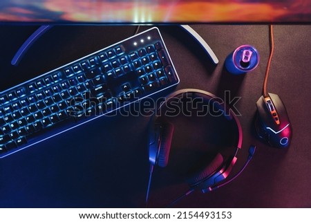 Close-up of black desktop with professional gaming and streaming setup, keyboard, monitor, computer mouse, headset. Gamer's equipment ready for online championship and streaming. Cyber sport concept