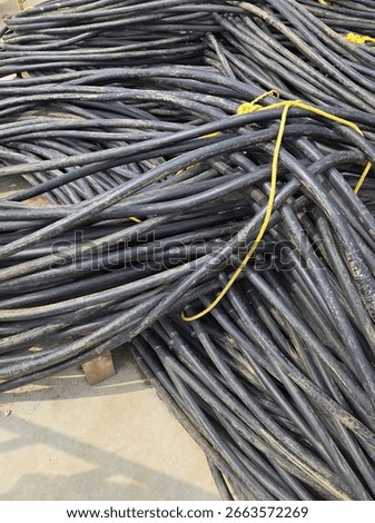 Close-up of a black electrical cable roll on the ground at an outdoor construction project.
