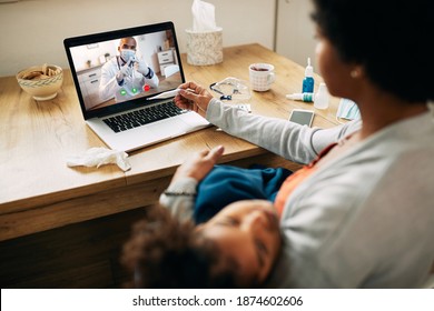Close-up Of Black Family Doctor Having Video Call With A Mother Who Is Measuring Daughter's Temperature At Home During Coronavirus Pandemic. 