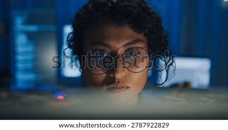 Close-up Black female programmer with code reflection in glasses working late in home office at night. Cybersecurity, AI algorithm, Network security, software developer, serious face, burnout concept.