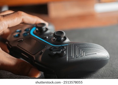 A close-up of a black gaming controller being held by a hand, resting on a gaming mouse pad. The background is softly blurred, emphasizing the controller's details.