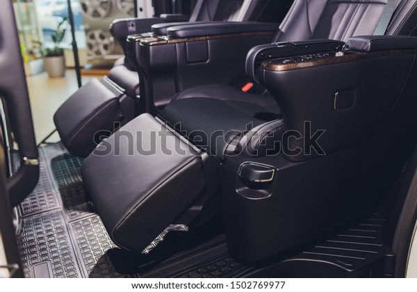 close-up of the black leather rear seats with\
footrest. modern car\
interior.