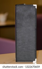 Close-up Of A Black Leather Restaurant Menu On A Table