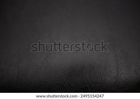 Close-up of a black leather texture with subtle cracks and natural patterns, ideal for backgrounds and design projects.