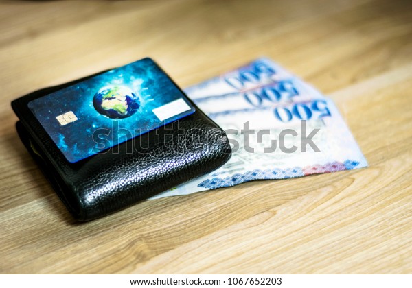 closeup of black leather\
wallet full of cash money and a remote key of a car and a bank\
credit card