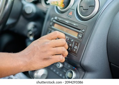 Close-up Of A Black Man's Hand Adjusts The Volume Of The Car Stereo System. The Driver Of The Car Switches Radio Stations On The Multimedia System Of His Car. Transport And Vehicle Concept