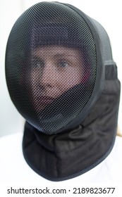 Closeup Of Black Metal Mask (helmet) On Female Head For Electric And Non-electric Sabre Fencing On White Background.  Weapon Safety, Protective Gear. Vertical Plane. 