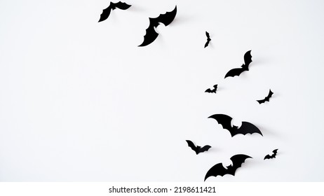 Closeup black paper bats on white wall,copy space,decor for holiday.Interior decoration concept for happy halloween,day of the dead celebration.Top view,flat lay. Holiday postcard.