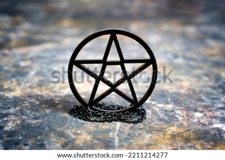 Close-up of a black pentagram necklace placed on a messy grungy background