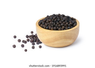Closeup black pepper seeds or peppercorns (dried seeds of piper nigrum) in wooden bowl isolated on white background.