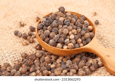 Cercado de semillas de pimienta negra o de pimienta (semillas secas de piper nigrum) en cuchara de madera