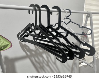 Close-up of black plastic hangers hanging on a white rack in a modern home setting. Perfect for organizing clothes efficiently. - Powered by Shutterstock