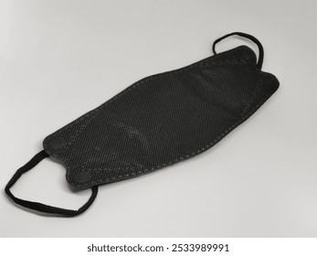 A close-up of a black protective face mask on a white background, ideal for promoting health, safety, or fashion-related content. - Powered by Shutterstock