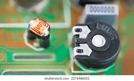 Closeup of black resistor trimmer and photoresistor with sensitive surface in a green PCB. Small electrical components on blurred printed circuit board detail. Optoelectronics in electronics industry.