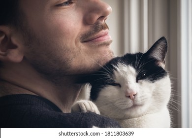 Closeup Of A Black And White Cat Cuddled By A Beard Man. Love Relationship Between Human And Cat