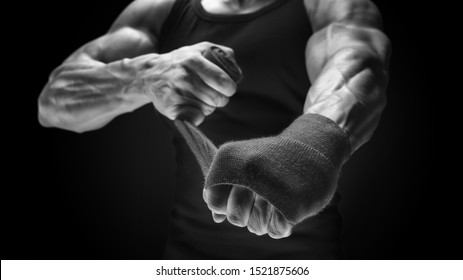 Close-up black and white photo of strong male hands Man is wrapping hands with boxing wraps isolated on black background Strong hands and fist, ready for training and active exercise - Powered by Shutterstock