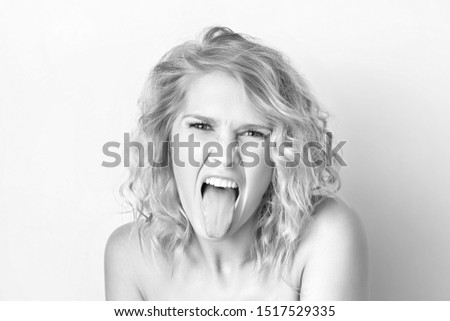 Closeup black and white portrait of woman with foolish grimace showing tongue isolated at white background. Concepy of joy and careless lifestyle. Funny emotion.