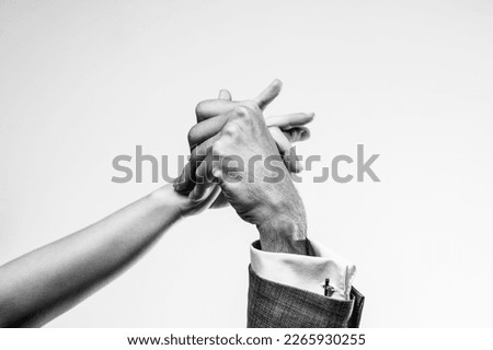 Close-up black and white shot of two tango dancers holding hands.
