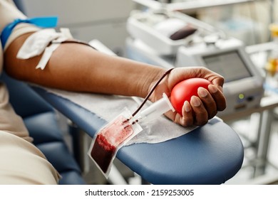 Closeup of black woman donating blood focus on hand holding red ball with tubing, copy space