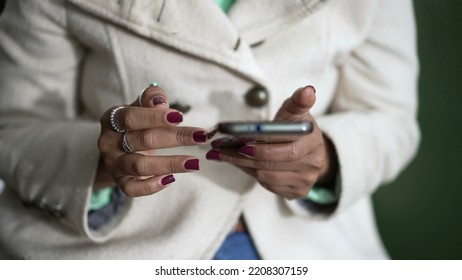 Closeup Of A Black Woman Hands Holding Cellphone Device Scrolling Screen. African American Person Holding Phone Touching Screen