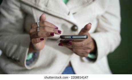 Closeup Of A Black Woman Hands Holding Cellphone Device Scrolling Screen. African American Person Holding Phone Touching Screen