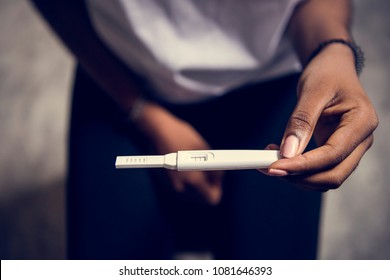 Closeup of black woman with pregnancy test in a hand