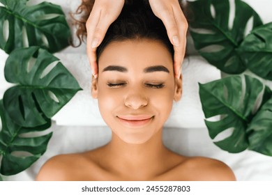 Close-up of a black woman receiving a soothing facial massage at a spa, highlighting relaxation and wellness amongst people - Powered by Shutterstock