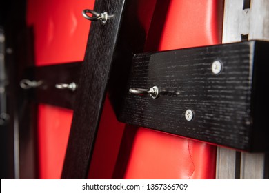 Close-up of black wooden cross on red wall. Bdsm bondage game.
