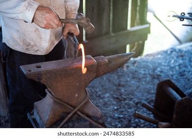 Close-up blacksmith man hand using long carbon steel tongs with steel rivets and hammer to forge cast iron horseshoes melting on medieval anvil at traditional trade workshop, Mansfield, Missouri. USA - Powered by Shutterstock