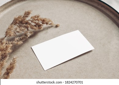 Closeup Of Blank Business Card Mockup. Dry Grass On Beige Ceramics Plate. Fall And Thanksgiving Concept. Autumn Styled Stock Still Life Photo. Selective Focus, No People.