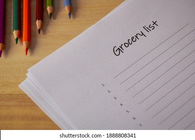 Close-up Of Blank Grocery List With Color Pencils On Wooden Desk. 